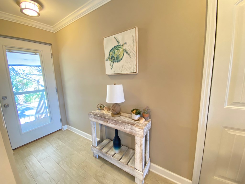 a entryway with a table with a lamp and a painting on the wall
