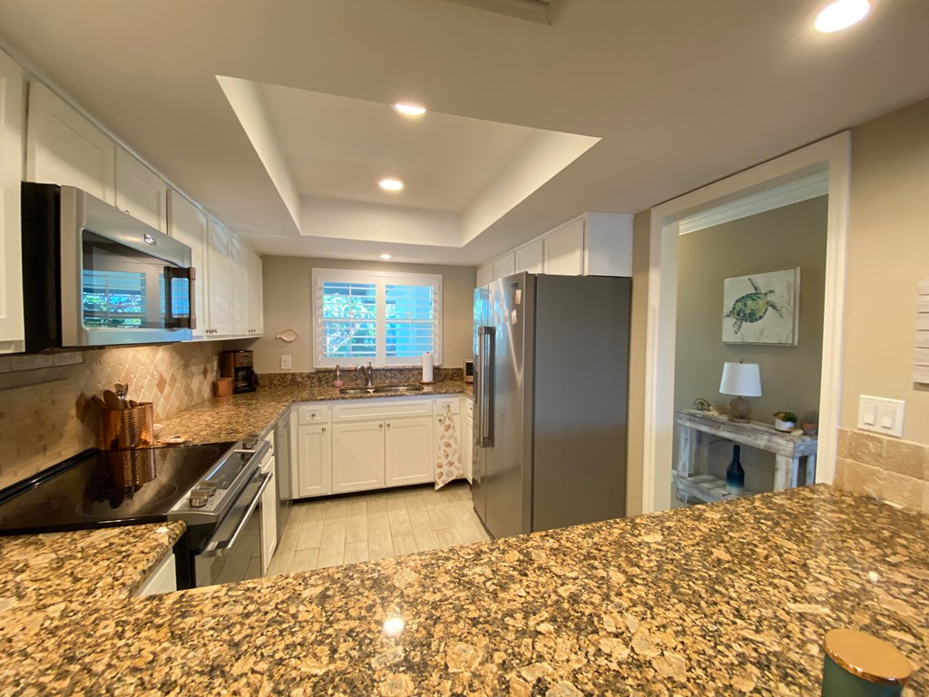 a kitchen with granite counter tops and a stainless steel refrigerator
