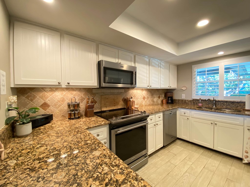 a kitchen with white cabinets and granite counter tops