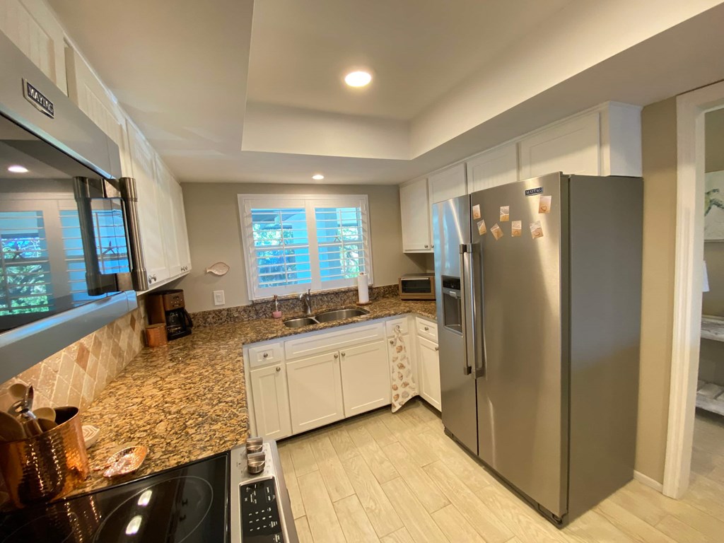 a kitchen with granite counter tops and a stainless steel refrigerator