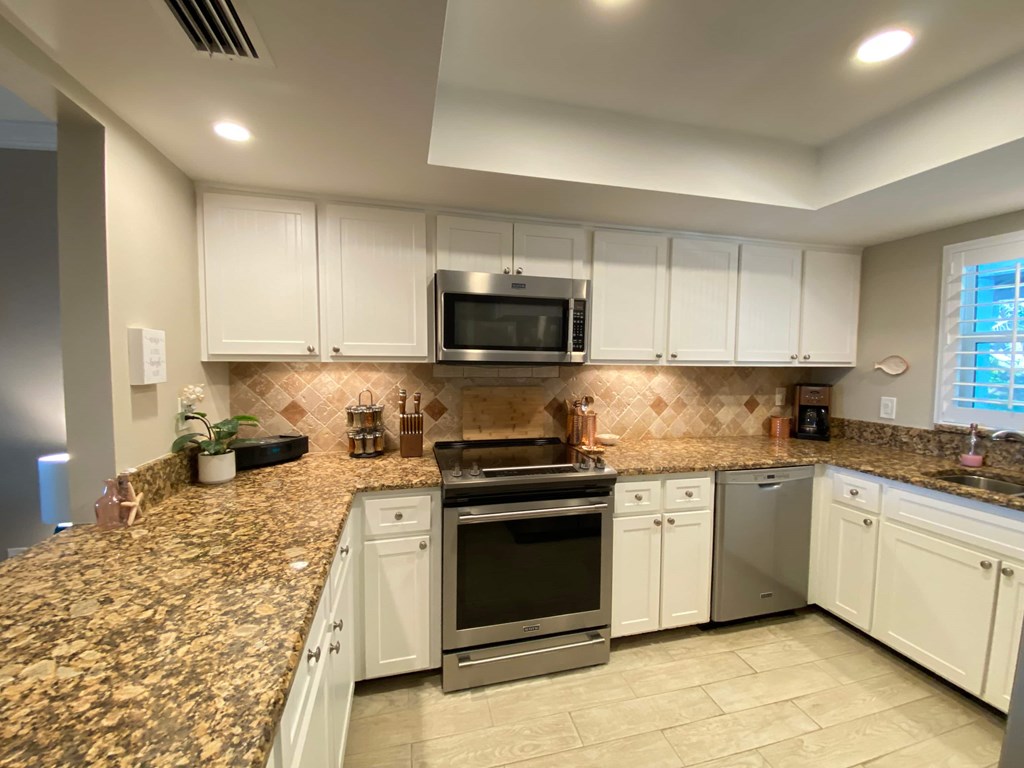a kitchen with white cabinets and a granite counter top
