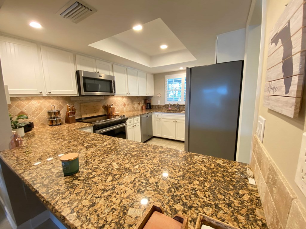 a kitchen with a granite counter top and a stainless steel refrigerator