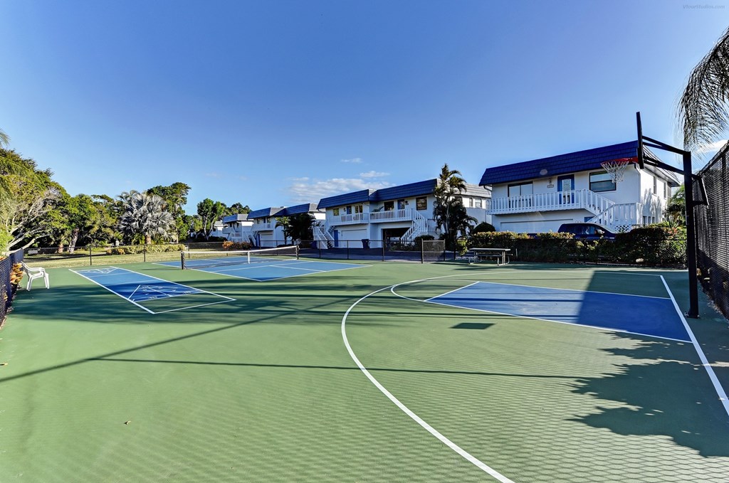 two tennis courts with houses in the background on a sunny day