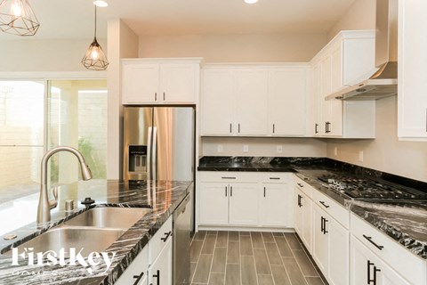 A kitchen with white cabinets and a black marble countertop.