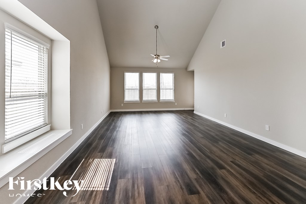 A spacious room with wooden floors and a ceiling fan.
