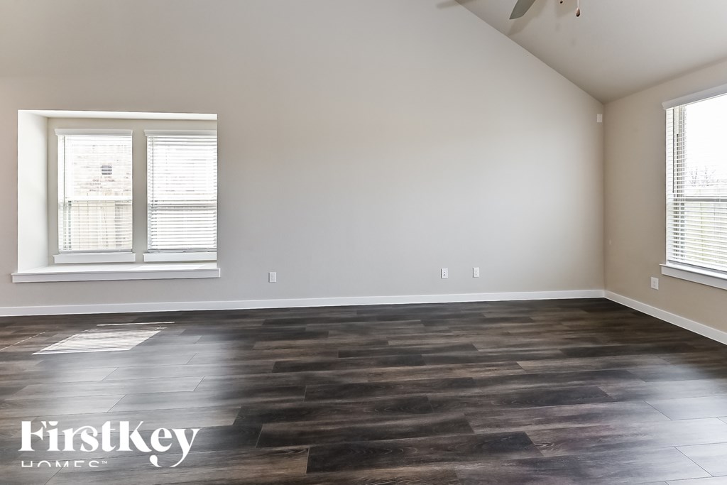 A room with wooden flooring and a window with blinds.