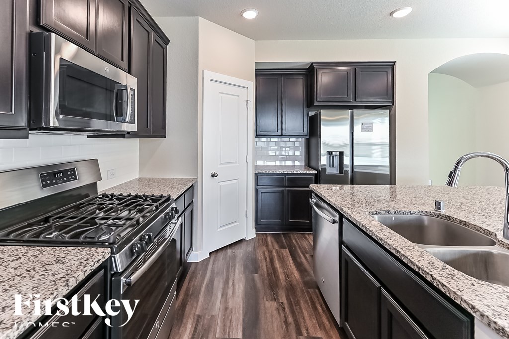 A kitchen with black cabinets and a stove top oven.
