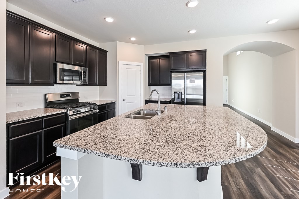 A kitchen with granite countertops and black cabinets.