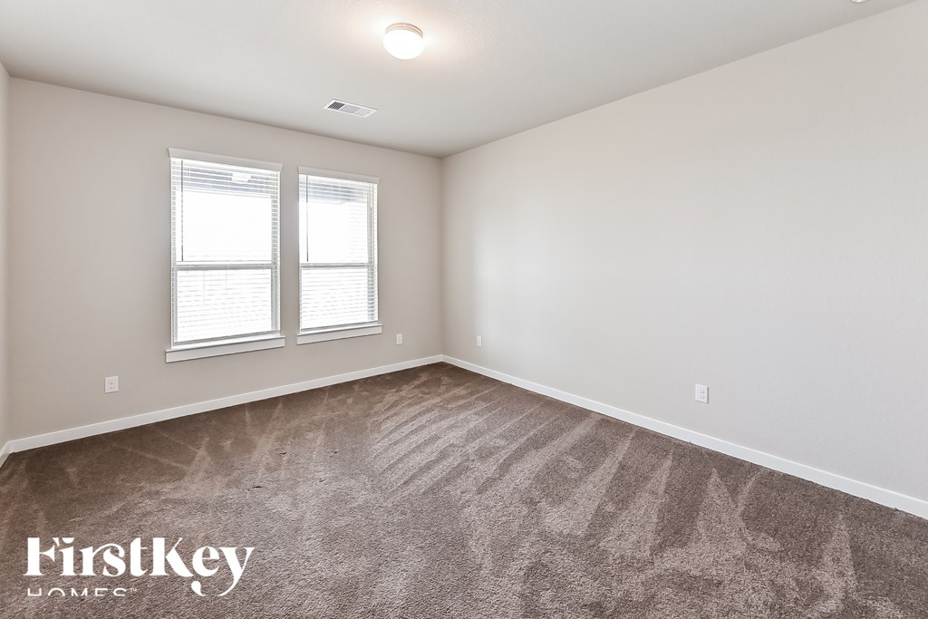 A room with a carpeted floor and two windows.