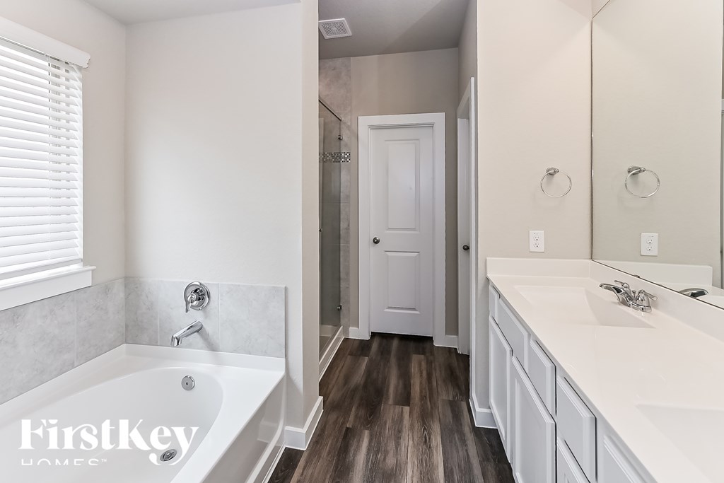 A white bathroom with a tub, sink and mirror.