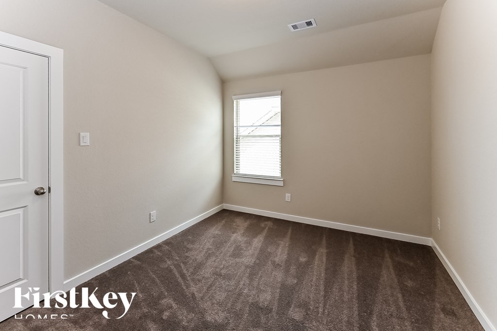 A room with a carpeted floor and a window with blinds.
