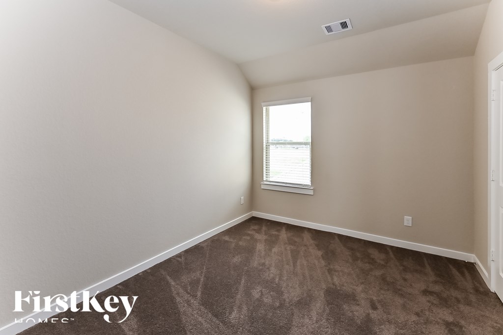 A room with a carpeted floor and a window with blinds.