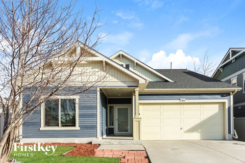 A house with a garage door and a tree in front of it.