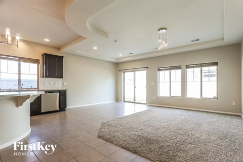 A spacious living room with a kitchen area in the background.