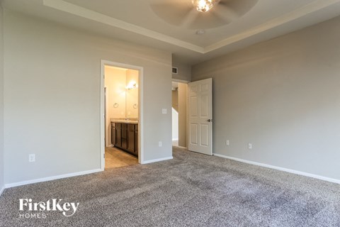 A spacious room with a carpeted floor and a ceiling fan.
