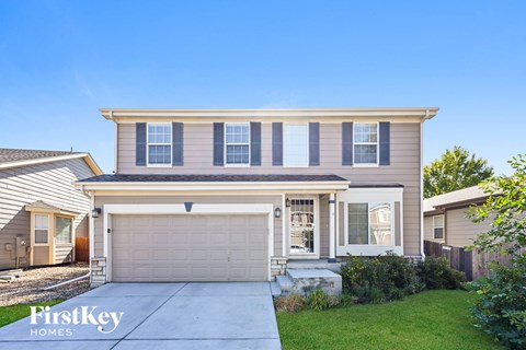 a beige house with a garage door and a driveway