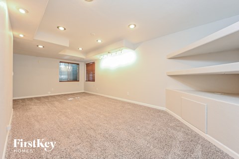 a basement with a carpeted floor and a white room with shelves and a window
