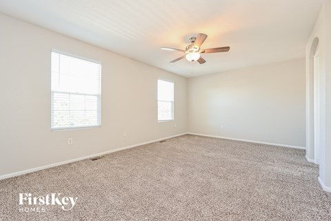a spacious living room with carpet and a ceiling fan