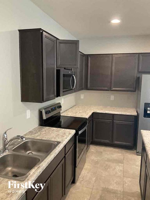 A kitchen with dark brown cabinets and a granite countertop.