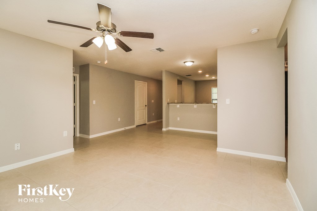 an empty living room and kitchen with a ceiling fan