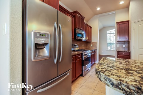 A modern kitchen with a stainless steel refrigerator and granite countertops.