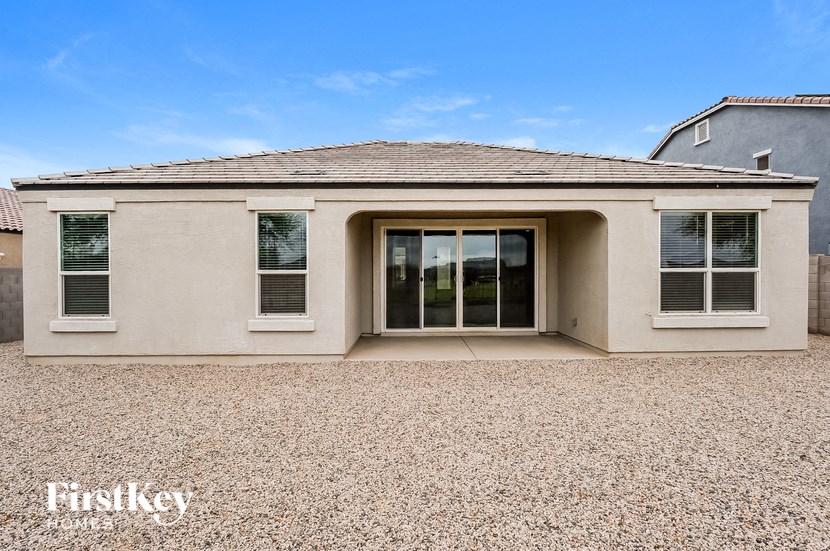 a beige house with a gravel yard and a door