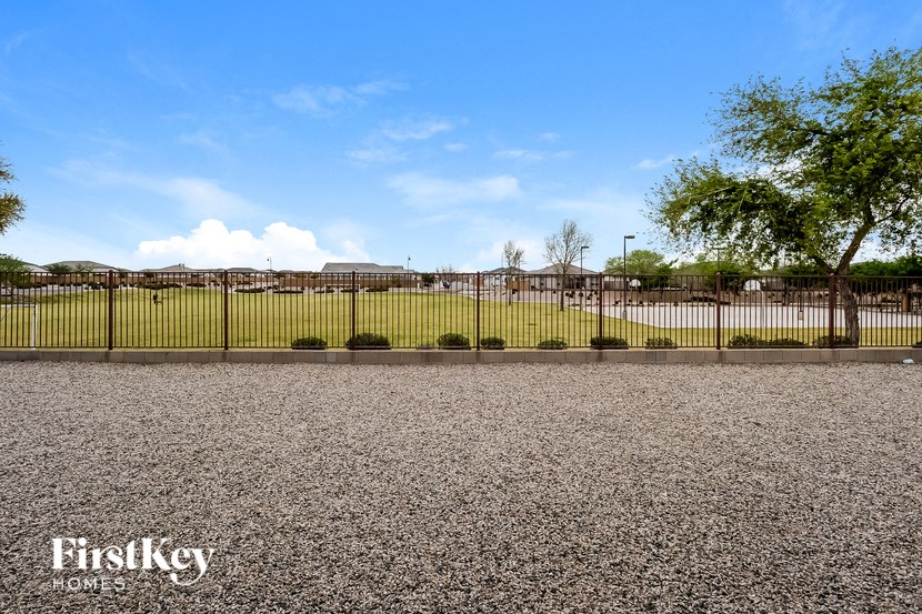 a large gravel driveway with a fence in front of a grass field