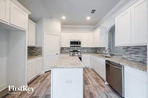 a kitchen with white cabinets and marble counter tops