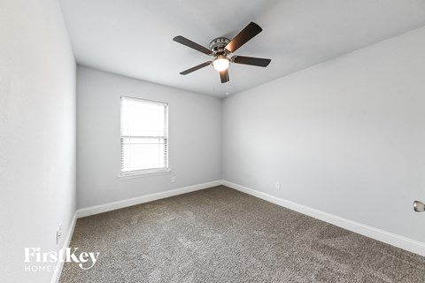 a bedroom with white walls and a ceiling fan