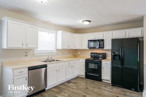 a kitchen with white cabinets and black appliances