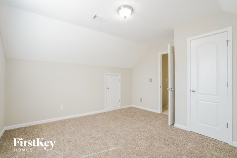 a bedroom with white walls and carpet and a door to a closet