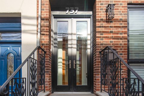 the front door of a brick building with two doors and a staircase