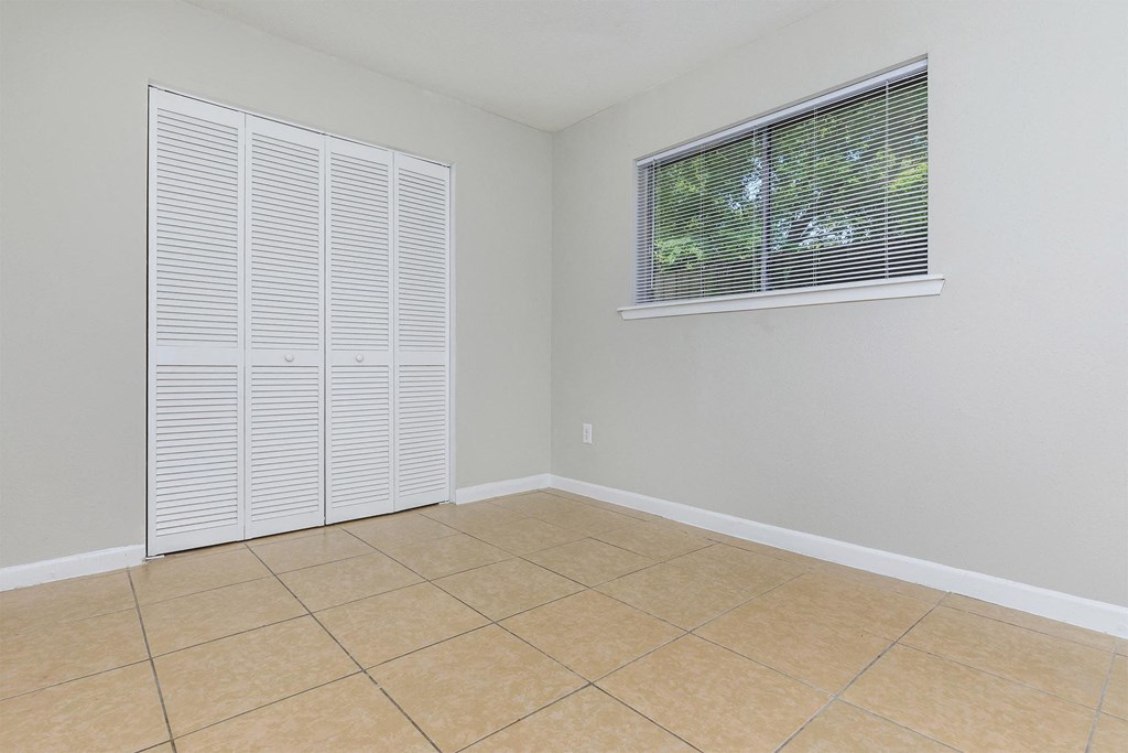 an empty room with a window and a tiled floor