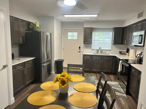 an open kitchen and dining room with a table and sunflowers