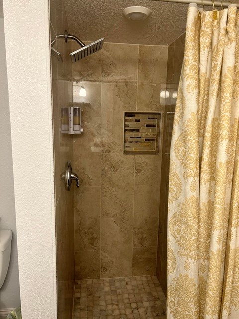 a tiled shower with a curtain in a bathroom