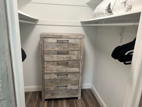 a dresser with drawers in a closet with shelves