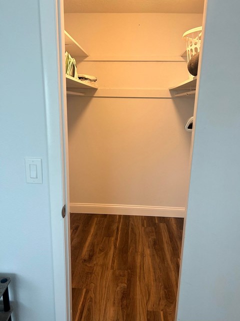 a walk in closet with shelves and a wood floor