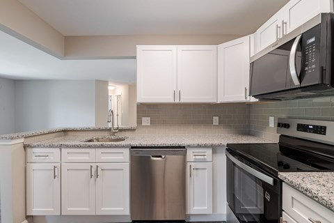 A kitchen with white cabinets and a granite countertop.