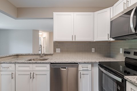 A kitchen with white cabinets and a granite countertop.
