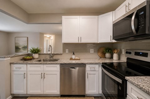 A modern kitchen with white cabinets and stainless steel appliances.