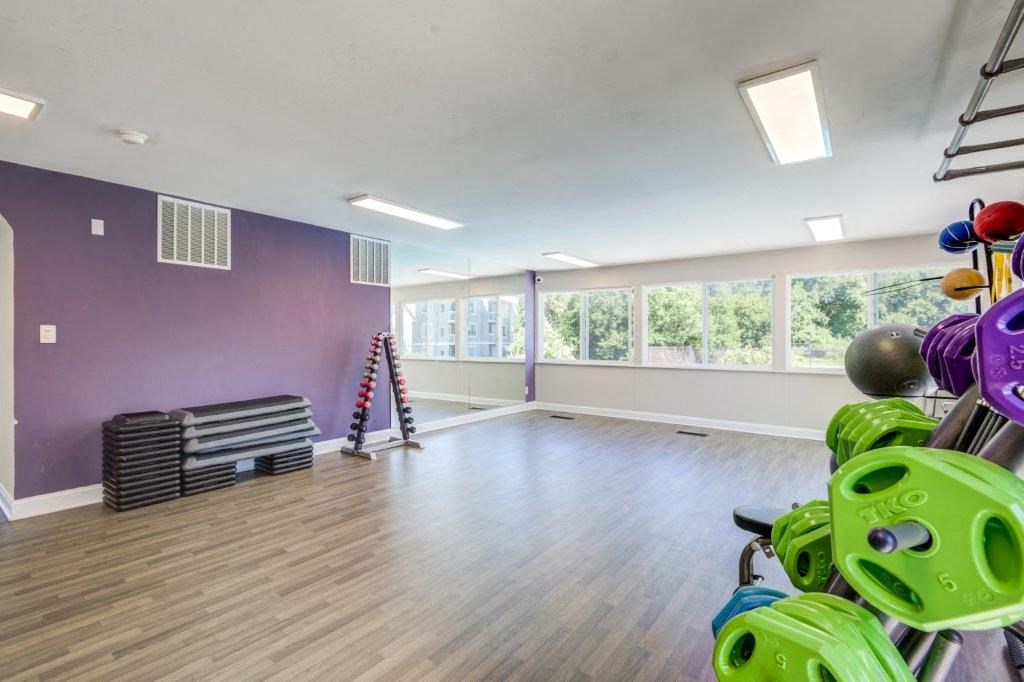 a workout room with weights and yoga equipment in a large room with windows