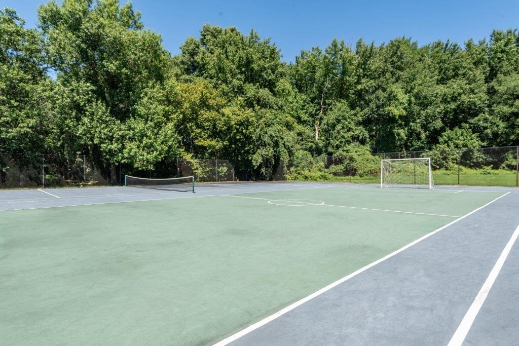 a tennis court with trees in the background on a sunny day