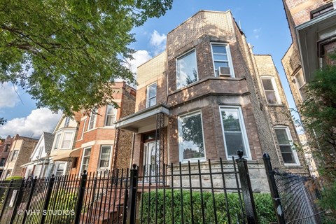 a brick house with a fence in front of it