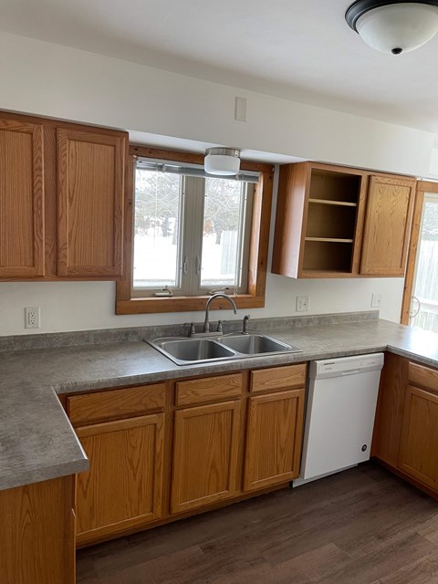 A kitchen with wooden cabinets and a white dishwasher.
