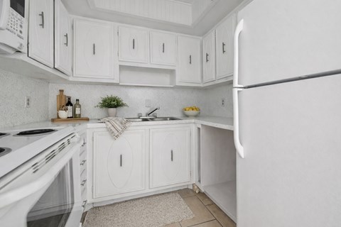 A white kitchen with a refrigerator on the right.