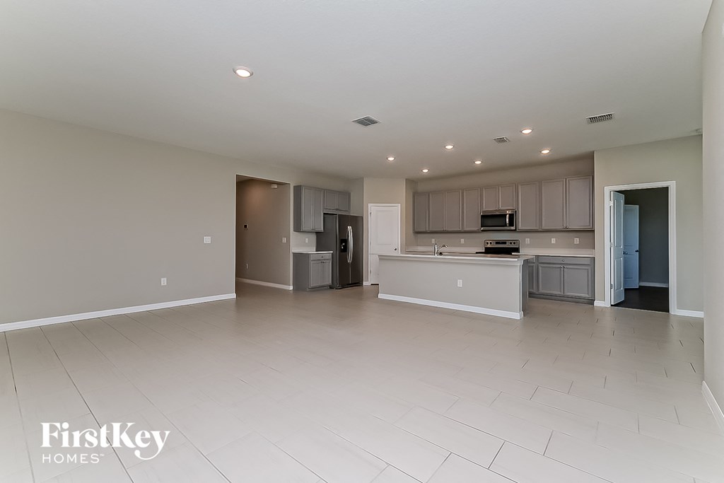 a large empty living room with a kitchen and