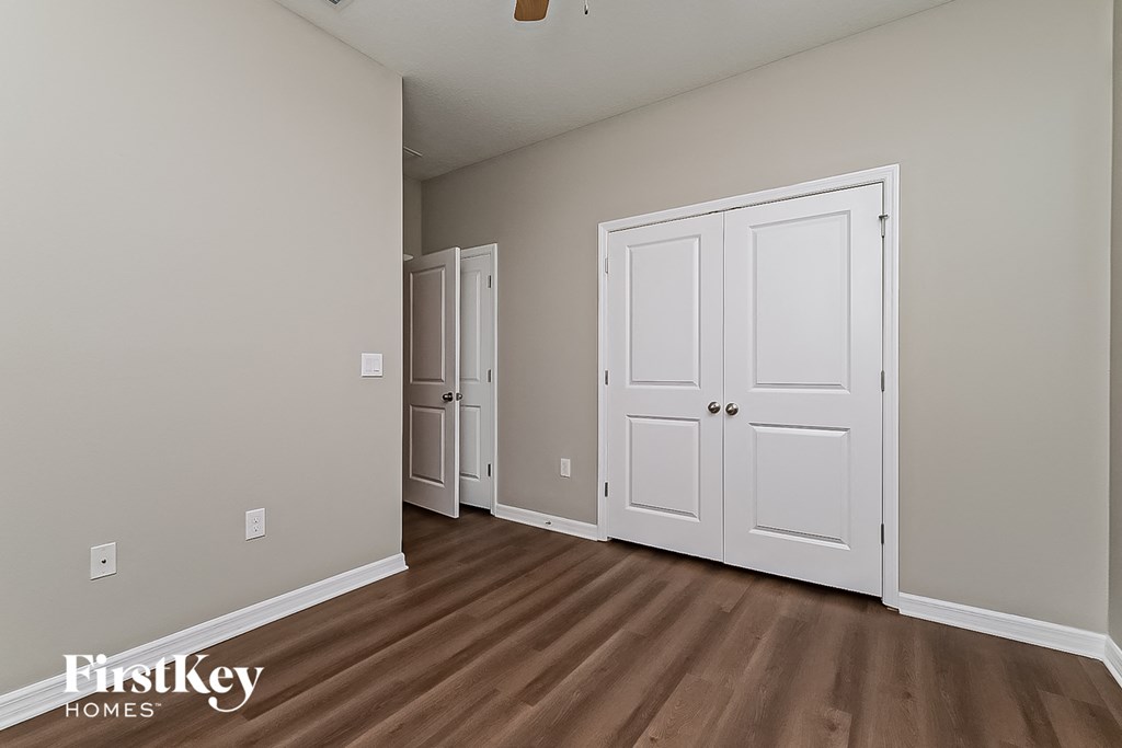 a bedroom with two closets and a hard wood floor