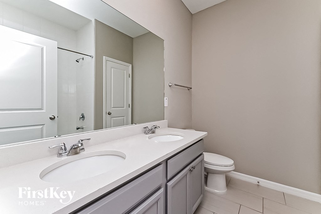 a bathroom with two sinks and a toilet and a mirror