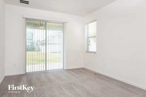 the living room of an apartment with a large window and a door to the yard