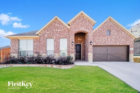 a brick house with a garage door and a lawn